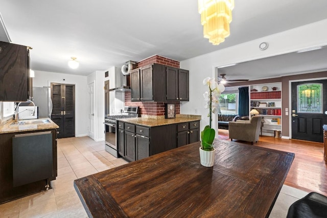 2621 W 45th St, Austin, TX 78731 - kitchen featuring stainless steel appliances, a sink, light tile patterned floors, light stone counters, and dark brown cabinets