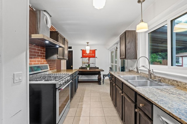 2621 W 45th St, Austin, TX 78731 - kitchen featuring stainless steel appliances, wall chimney exhaust hood, a sink, and decorative light fixtures