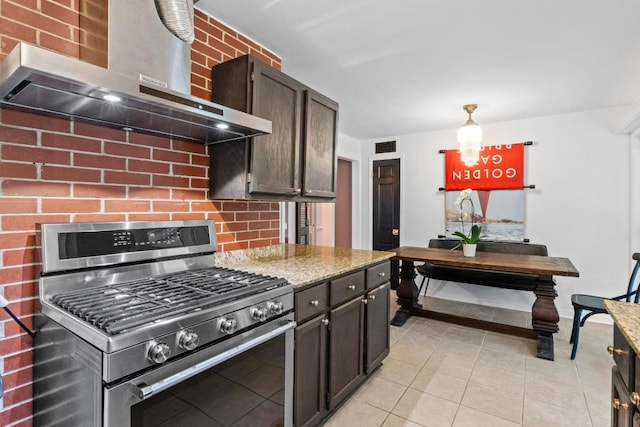 2621 W 45th St, Austin, TX 78731 - kitchen featuring stainless steel range with gas stovetop, wall chimney exhaust hood, light tile patterned floors, dark brown cabinets, and decorative backsplash