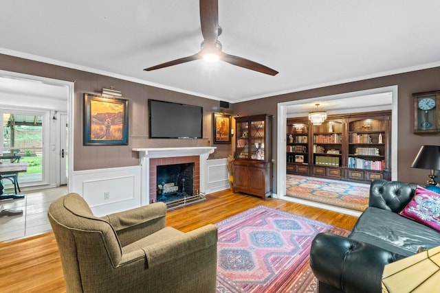 2621 W 45th St, Austin, TX 78731 - living area with a ceiling fan, wood finished floors, crown molding, a fireplace, and a decorative wall