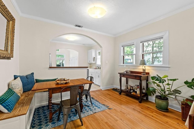 605 E 43rd St, Austin, TX 78751 - dining space featuring light wood-style flooring, arched walkways, and crown molding