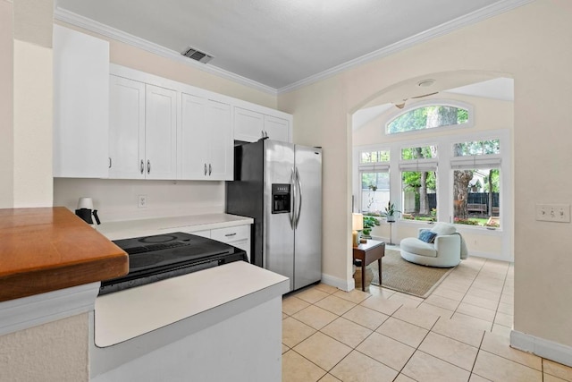 605 E 43rd St, Austin, TX 78751 - kitchen featuring stainless steel refrigerator with ice dispenser, white cabinets, ornamental molding, light countertops, and arched walkways
