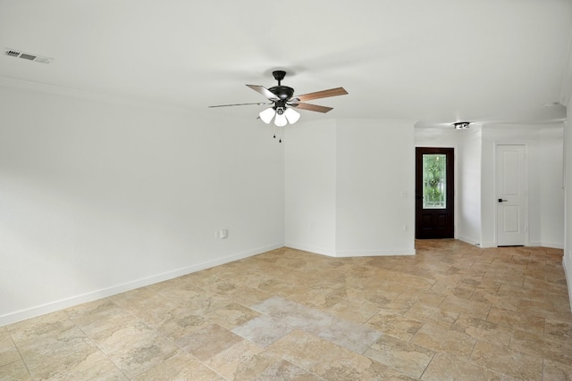 spare room with crown molding, a ceiling fan, light stone finish flooring, and baseboards