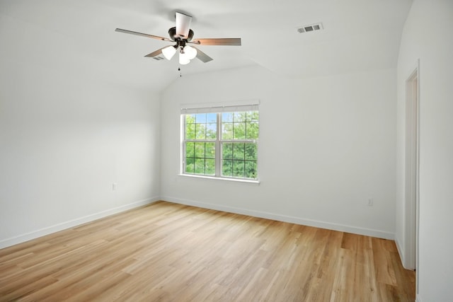 spare room featuring baseboards, ceiling fan, lofted ceiling, and light wood finished floors