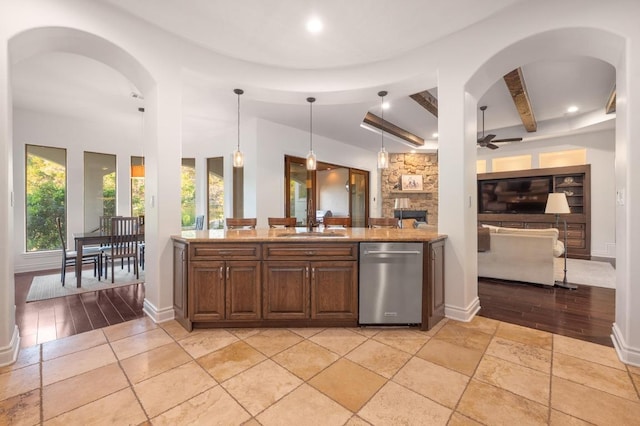 kitchen with stainless steel dishwasher, arched walkways, beam ceiling, healthy amount of natural light, and recessed lighting