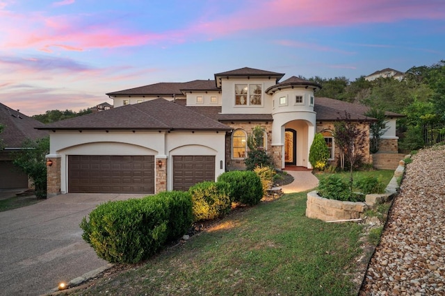 mediterranean / spanish house with stucco siding, driveway, an attached garage, and stone siding
