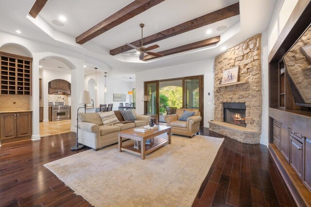 4105 Michael Neill Dr, Austin, TX 78730 - living area with a stone fireplace, a ceiling fan, hardwood / wood-style flooring, arched walkways, and beam ceiling
