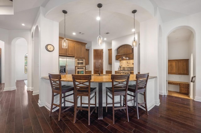 kitchen with stainless steel fridge, a peninsula, light stone countertops, baseboards, and dark wood finished floors