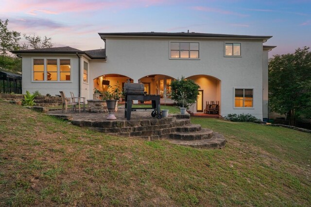 4105 Michael Neill Dr, Austin, TX 78730 - back of property at dusk featuring a patio, stucco siding, and a lawn