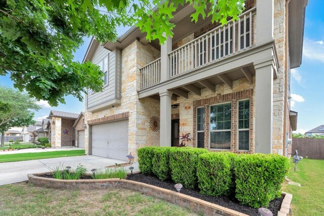 3624 Anchor Bay Dr, Pflugerville, TX 78660 - view of front of home with stone siding, an attached garage, a balcony, and driveway