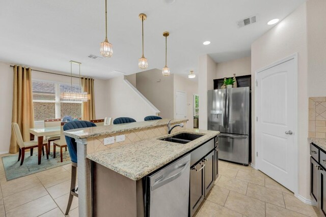 3624 Anchor Bay Dr, Pflugerville, TX 78660 - kitchen featuring stainless steel appliances, a sink, a kitchen breakfast bar, decorative light fixtures, and light tile patterned floors