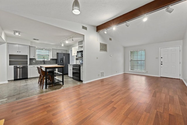 7004 Priscilla Dr, Austin, TX 78752 - living area featuring track lighting, wood finished floors, baseboards, and a textured ceiling