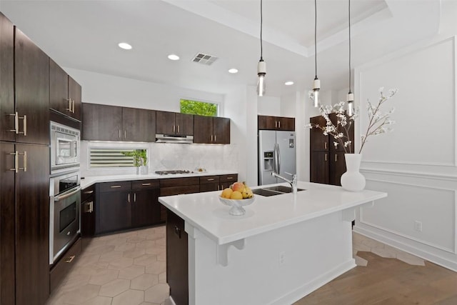 1500 Summit St Unit 5, Austin, TX 78741 - kitchen featuring appliances with stainless steel finishes, a sink, under cabinet range hood, light countertops, and tasteful backsplash