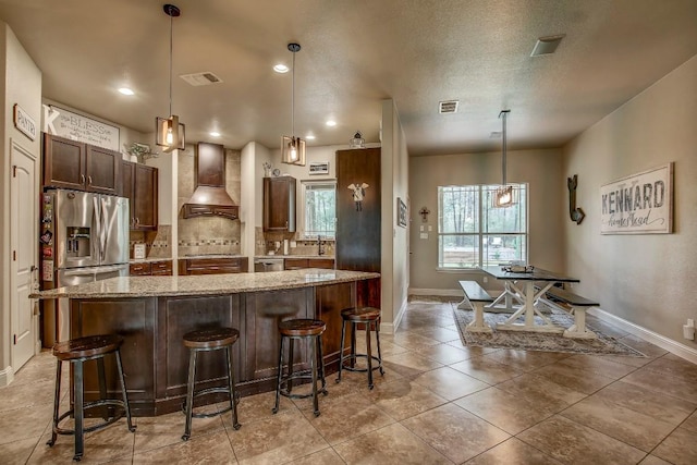 115 Loblolly Ln, Bastrop, TX 78602 - kitchen featuring custom exhaust hood, a center island, backsplash, light stone counters, and baseboards