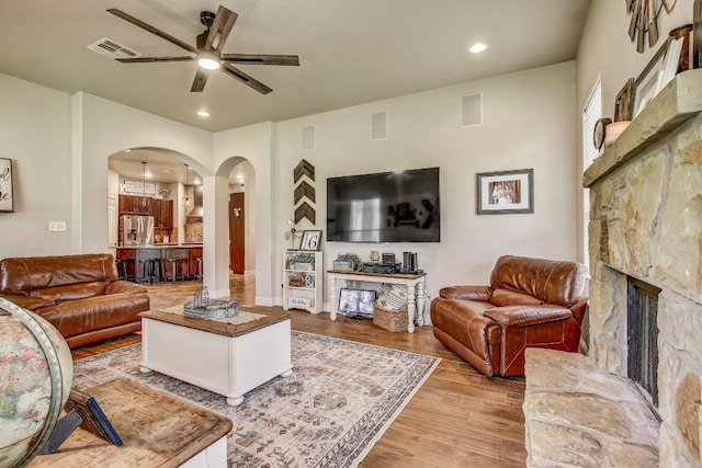 115 Loblolly Ln, Bastrop, TX 78602 - living room featuring arched walkways, ceiling fan, wood finished floors, a stone fireplace, and recessed lighting