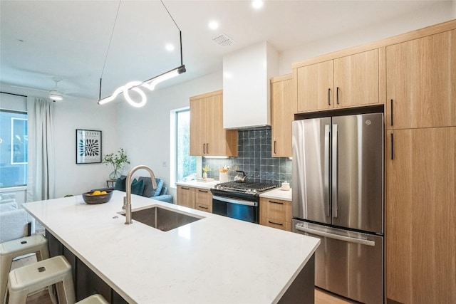 700 Denson Dr Unit 1101, Austin, TX 78752 - kitchen with appliances with stainless steel finishes, a sink, light brown cabinets, tasteful backsplash, and an island with sink