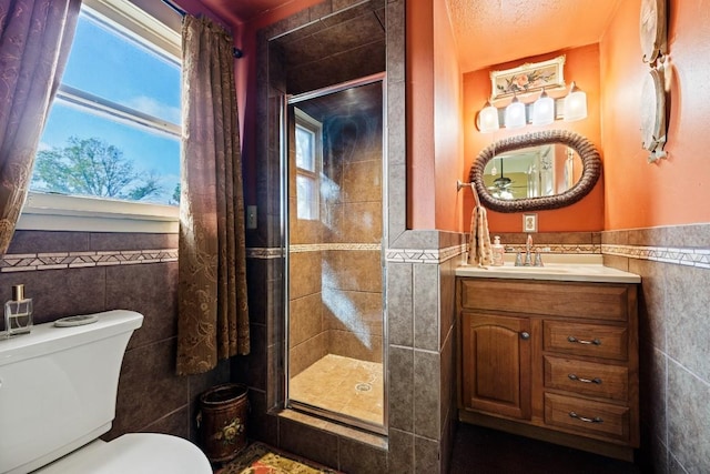 303 Austin St, Fredericksburg, TX 78624 - bathroom with tile walls, a stall shower, toilet, a wainscoted wall, and vanity