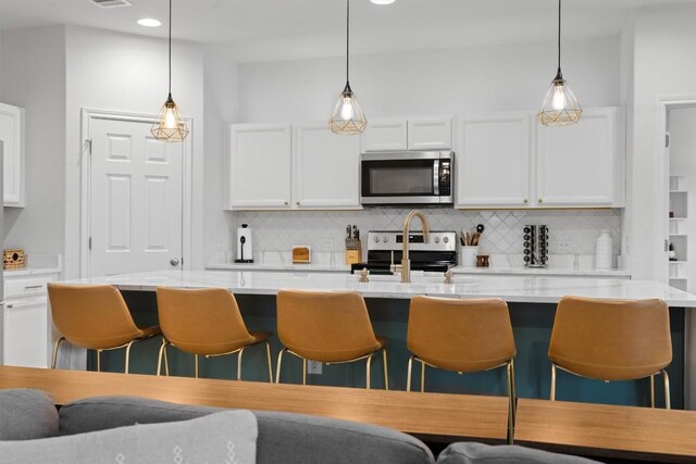 kitchen with appliances with stainless steel finishes, tasteful backsplash, a breakfast bar area, light countertops, and recessed lighting