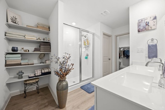 110 Johnson Draw Rd, Hutto, TX 78634 - bathroom with wood finished floors, a shower stall, a spacious closet, and double vanity