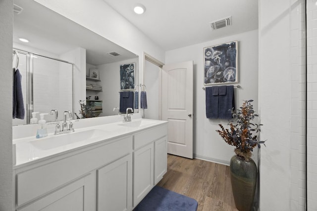 110 Johnson Draw Rd, Hutto, TX 78634 - bathroom featuring wood finished floors, double vanity, an enclosed shower, and recessed lighting