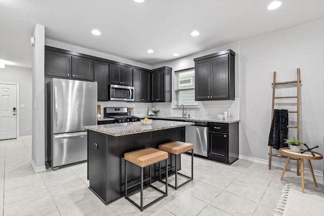1808 Pecan Island Dr, Leander, TX 78641 - kitchen with appliances with stainless steel finishes, a center island, light stone counters, dark cabinets, and recessed lighting