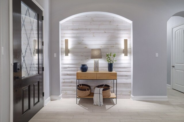 entryway featuring arched walkways, wood finished floors, and baseboards