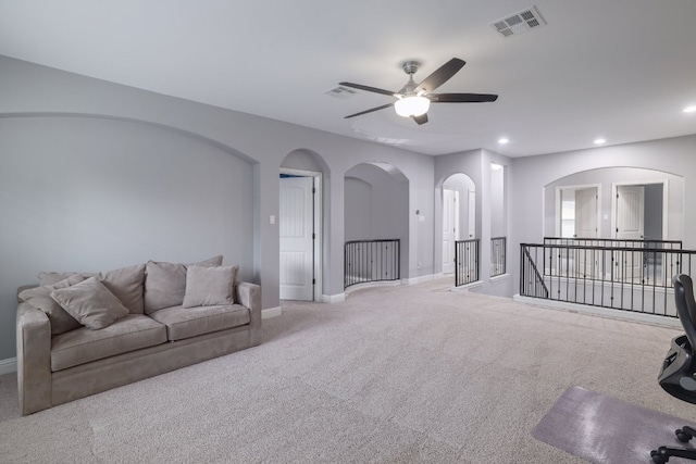 living area featuring carpet, baseboards, ceiling fan, recessed lighting, and arched walkways