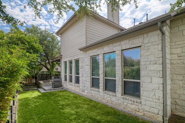 view of side of home with a chimney, stone siding, and a patio area