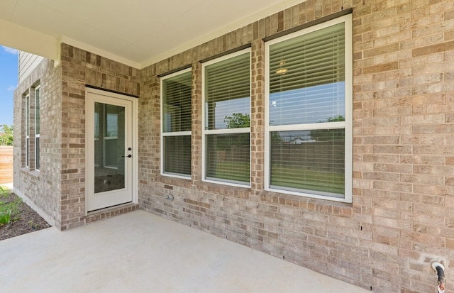 doorway to property featuring brick siding and a patio