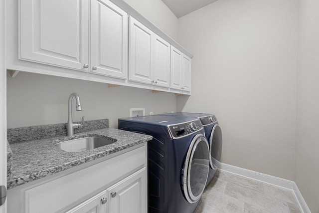clothes washing area with cabinet space, washing machine and clothes dryer, and baseboards