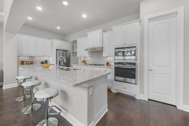 kitchen with a sink, backsplash, dark wood finished floors, white cabinetry, and recessed lighting