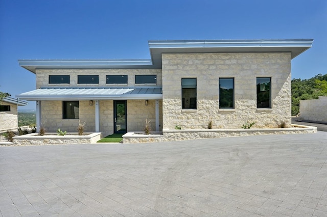 1785 Backbone Rdg, Wimberley, TX 78666 - modern home featuring a standing seam roof, stone siding, and metal roof
