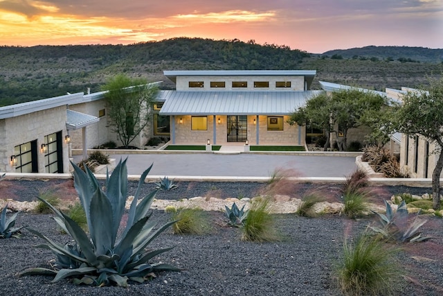 1785 Backbone Rdg, Wimberley, TX 78666 - back of property at dusk with stone siding, metal roof, and a porch