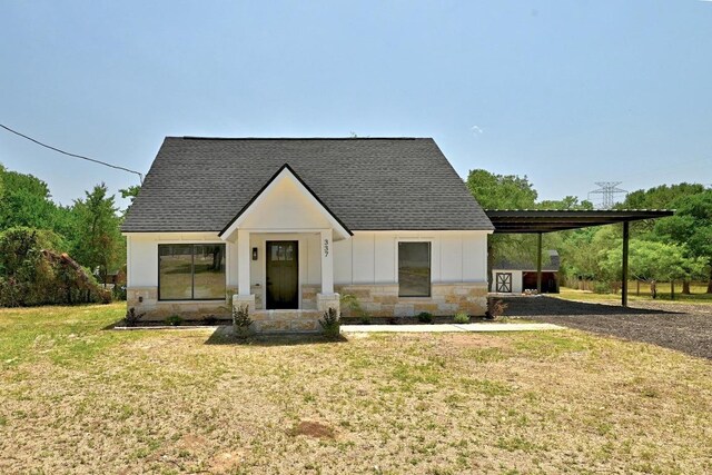 337 Forest Lake Dr, Del Valle, TX 78617 - modern inspired farmhouse with stone siding, a shingled roof, a front yard, an attached carport, and board and batten siding