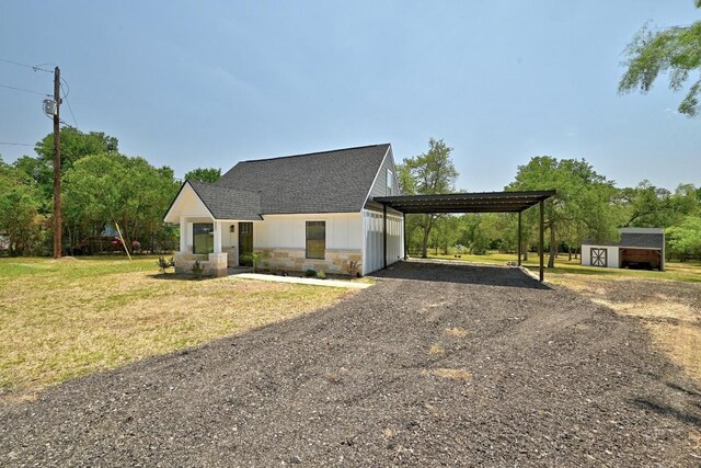 337 Forest Lake Dr, Del Valle, TX 78617 - view of front facade featuring dirt driveway, a shed, stone siding, a shingled roof, and a front yard