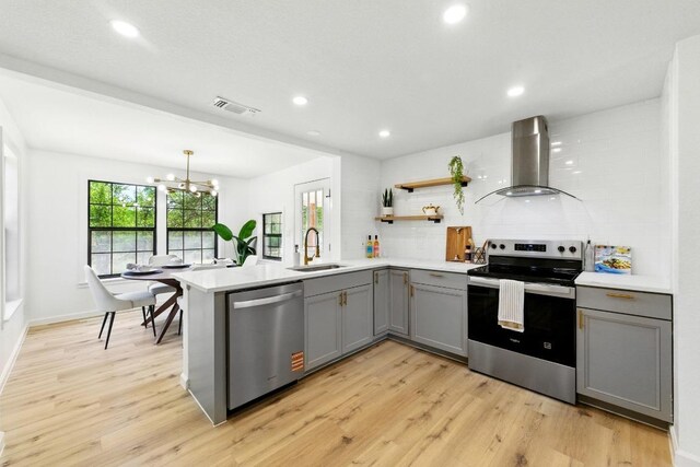 337 Forest Lake Dr, Del Valle, TX 78617 - kitchen with extractor fan, stainless steel appliances, gray cabinetry, a peninsula, and light countertops