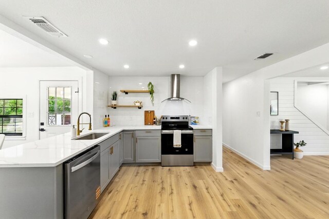 337 Forest Lake Dr, Del Valle, TX 78617 - kitchen featuring gray cabinets, stainless steel appliances, wall chimney exhaust hood, light wood finished floors, and open shelves