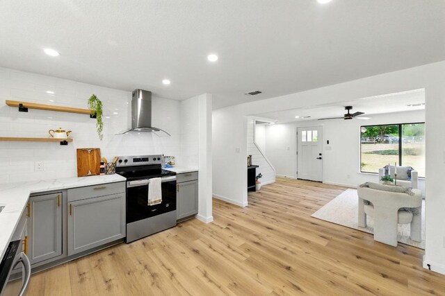 337 Forest Lake Dr, Del Valle, TX 78617 - kitchen with stainless steel electric range, wall chimney exhaust hood, gray cabinets, light wood-style floors, and recessed lighting
