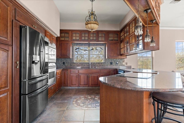 2604 Saratoga Dr, Austin, TX 78733 - kitchen with stainless steel appliances, a peninsula, tasteful backsplash, and glass insert cabinets