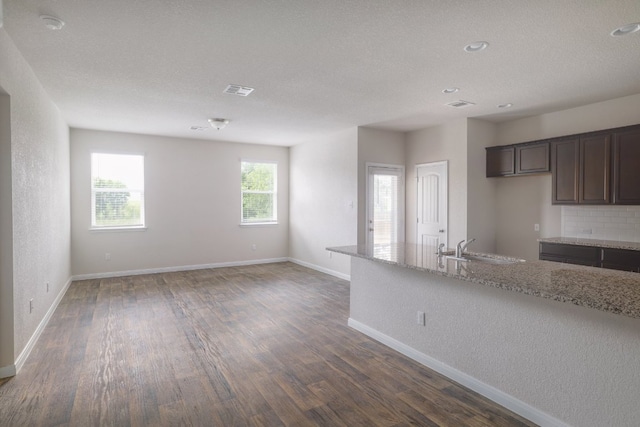 kitchen with dark wood-style flooring, light stone counters, baseboards, a sink, and recessed lighting