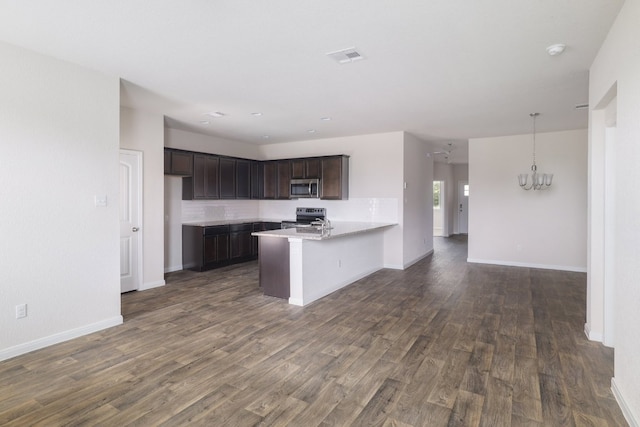 kitchen with appliances with stainless steel finishes, a peninsula, dark brown cabinets, and dark wood-style flooring