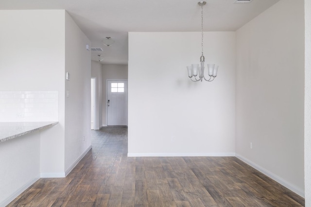 unfurnished dining area with a chandelier, dark wood-style floors, and baseboards