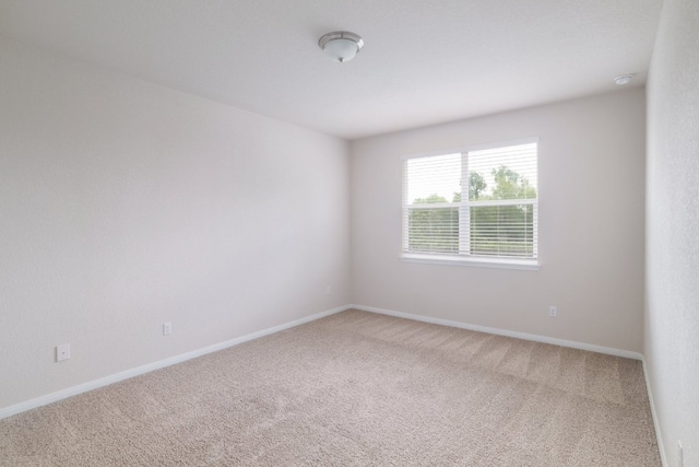 carpeted spare room featuring baseboards