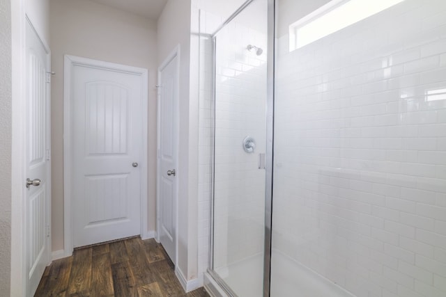 full bathroom with a stall shower, wood finished floors, and baseboards