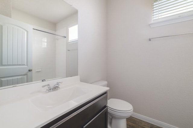 bathroom with toilet, healthy amount of natural light, vanity, and wood finished floors