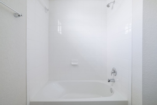 full bathroom with a textured wall and  shower combination