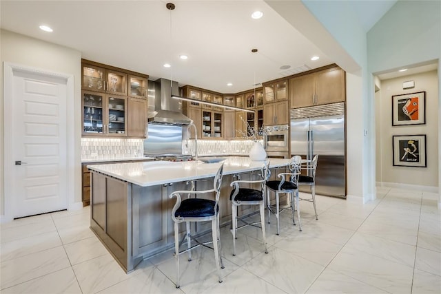 2212 Normandy Vw, Leander, TX 78641 - kitchen with stainless steel appliances, wall chimney range hood, decorative backsplash, brown cabinetry, and recessed lighting