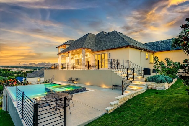2212 Normandy Vw, Leander, TX 78641 - back of property at dusk with stucco siding, a patio area, stairs, a pool with connected hot tub, and a lawn