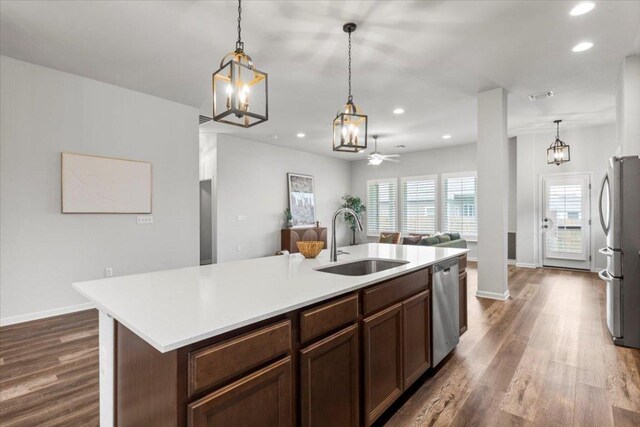 kitchen featuring a sink, appliances with stainless steel finishes, dark wood-type flooring, open floor plan, and recessed lighting
