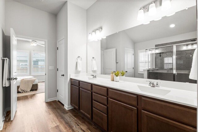 full bathroom with wood finished floors, a stall shower, double vanity, ensuite bath, and a ceiling fan